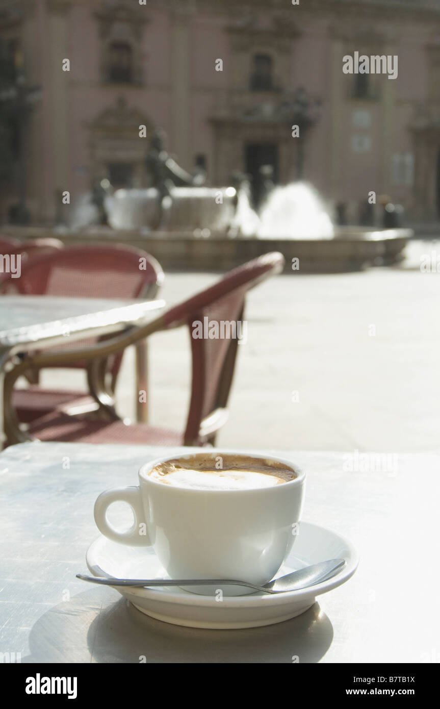 Taza de café con leche en la mesa en el exterior cafe' en la plaza de la vergen en Valencia España Foto de stock