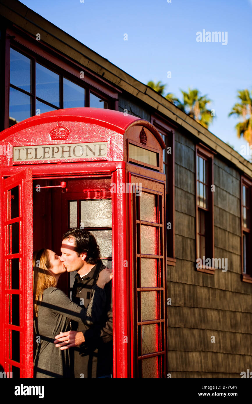 Un beso romántico en pareja en una cabina de teléfono rojo. Foto de stock