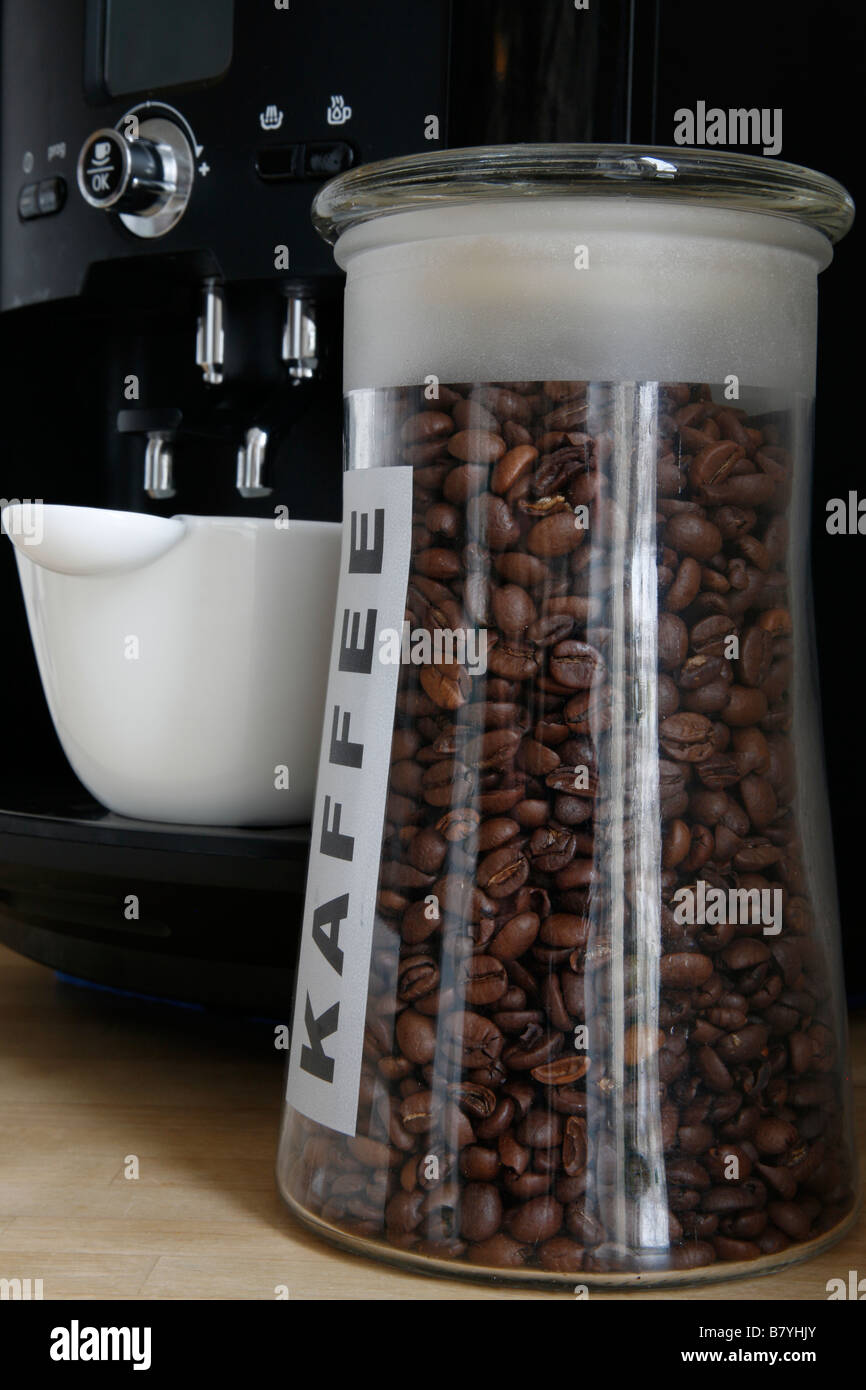 Sin moler granos de café tostado en una botella banco en frente de una taza  en la cafetera eléctrica, cafetera Fotografía de stock - Alamy