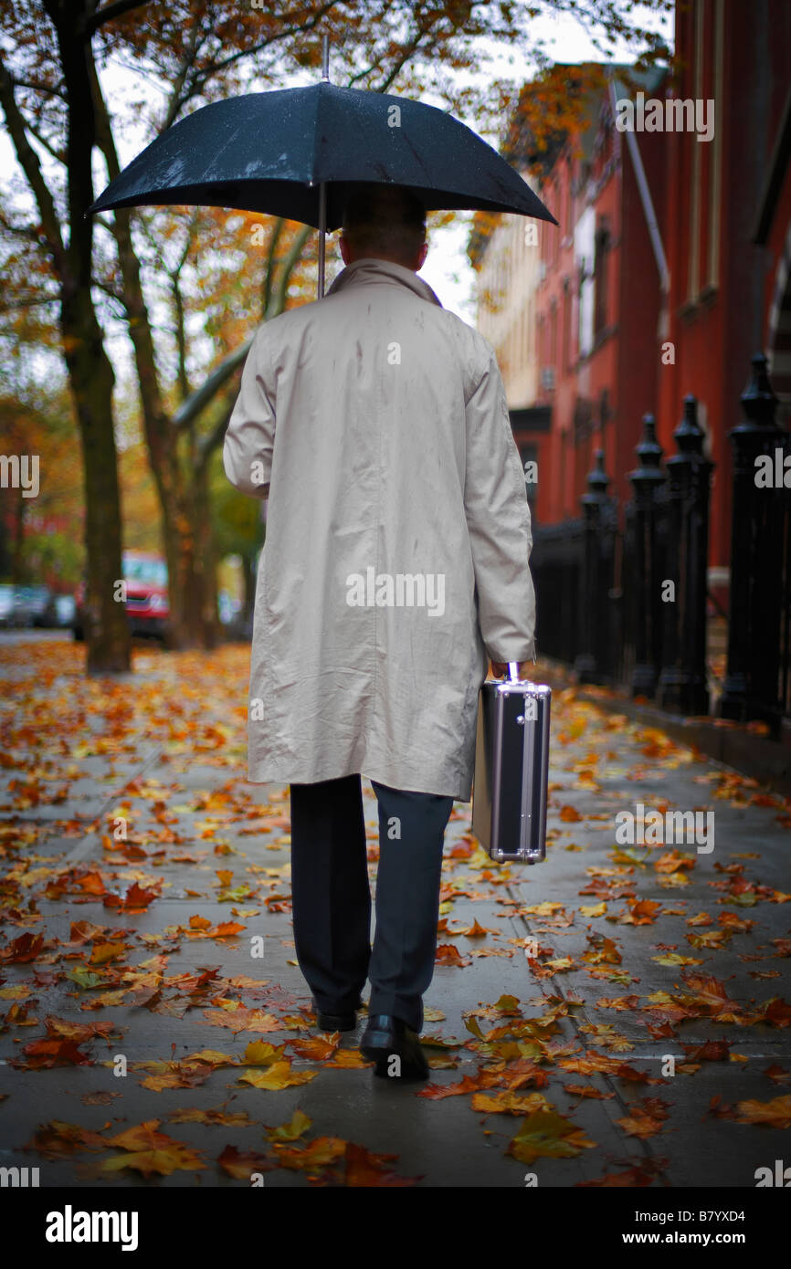 Hombre caminando en la calle bajo paraguas Foto de stock