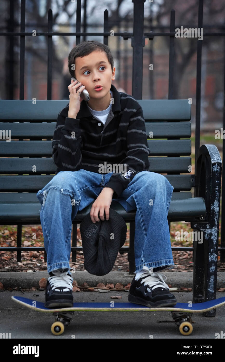 Adolescente con el monopatín a través de teléfono móvil Foto de stock