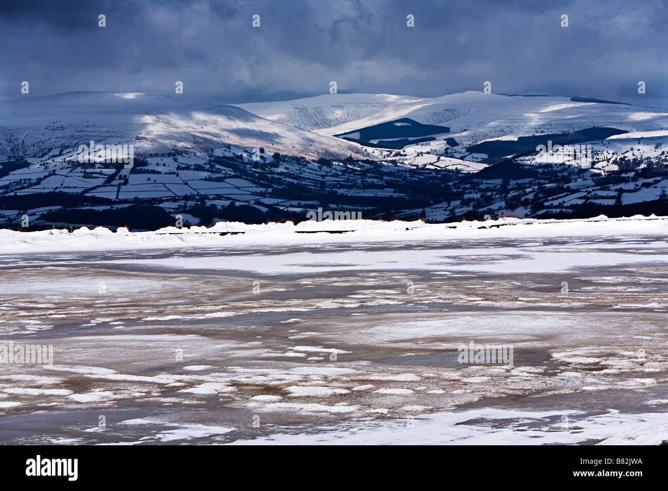 Fijadores estanque congelado en invierno con Montañas Negras en distancia Blorenge Gales UK Foto de stock