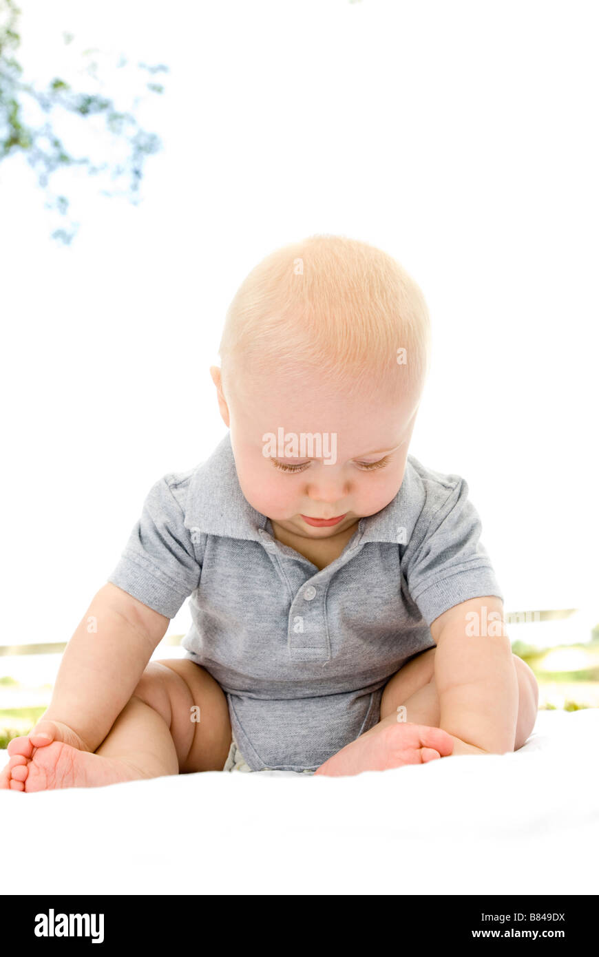 Bebé de 4 meses de edad sentado con los pies descalzos sobre una alfombra.  Juguetes en primer plano Fotografía de stock - Alamy