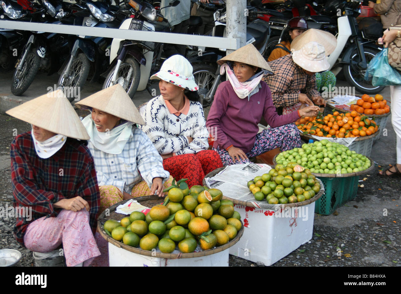 Impresionante fotografía de un grupo de vietnamitas señoras vendiendo frutas en un mercado en Hue, Vietnam (todos en busca de la misma manera). Foto de stock