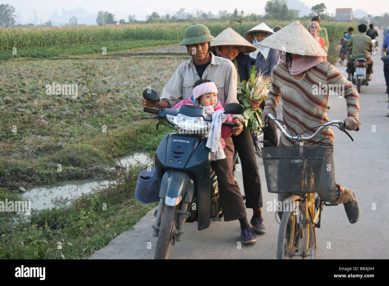 Retrato de una joven familia Vietnamita en una motocicleta cerca de un campo de Vietnam Foto de stock