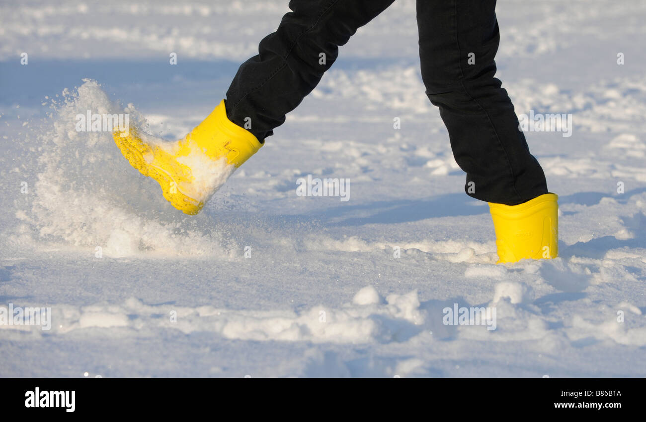 Una joven mujer vistiendo amarillo botas crocs chapuleteando en la nieve.  Fotografía por Jim Holden Fotografía de stock - Alamy