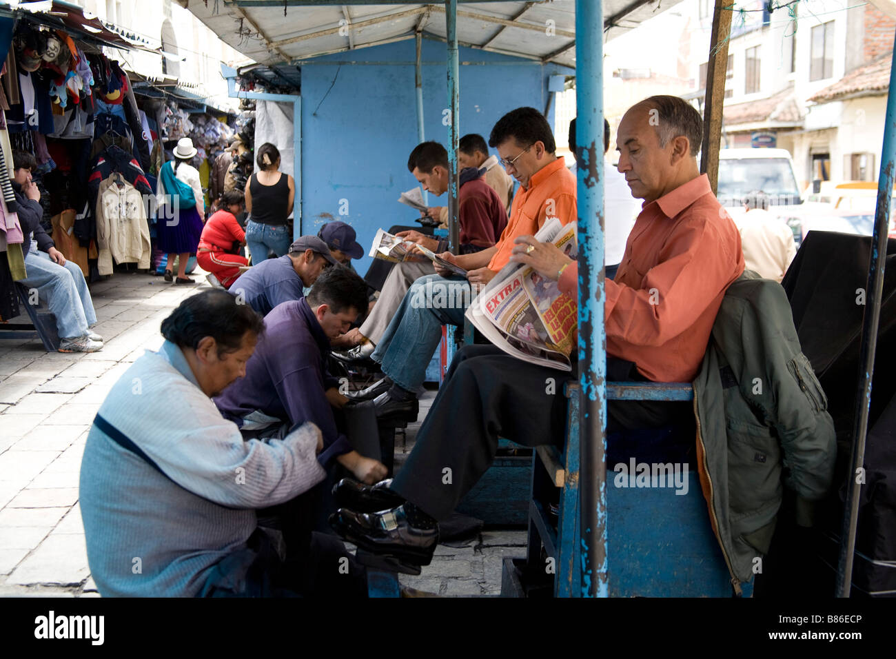La gente sentada leyendo periódicos mientras limpiabotas trabajadores suyos  limpia zapatos. Ecuador 72063 Cuenca Fotografía de stock - Alamy