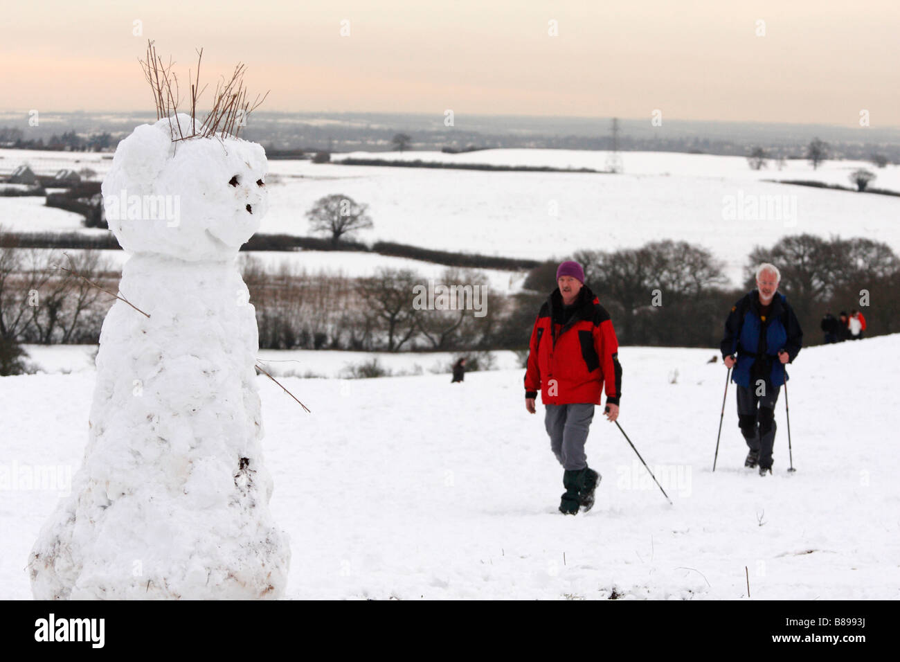 Muñeco de nieve y caminantes en el campo cubierto de nieve, el paisaje invernal escena, Oxfordshire, Inglaterra, Reino Unido. Foto de stock