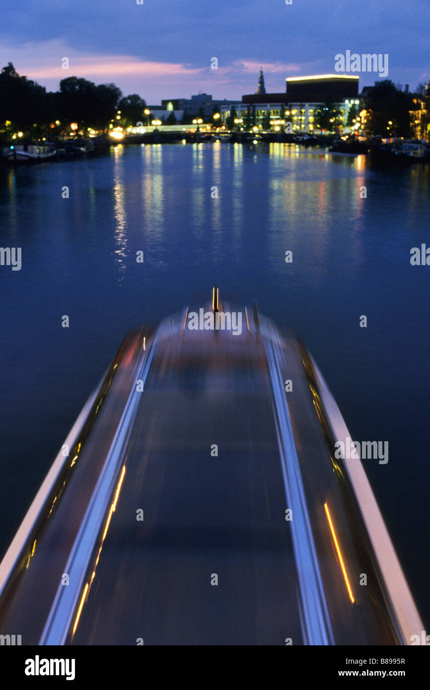 Un barco de crucero del canal oeste a lo largo del río Amstel en la noche en Amsterdam, Países Bajos. Foto de stock