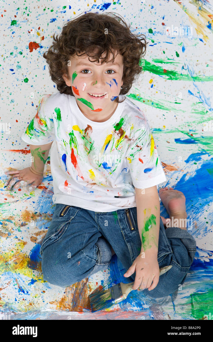 Guapo muchacho jugando con la pintura con el fondo pintado Foto de stock