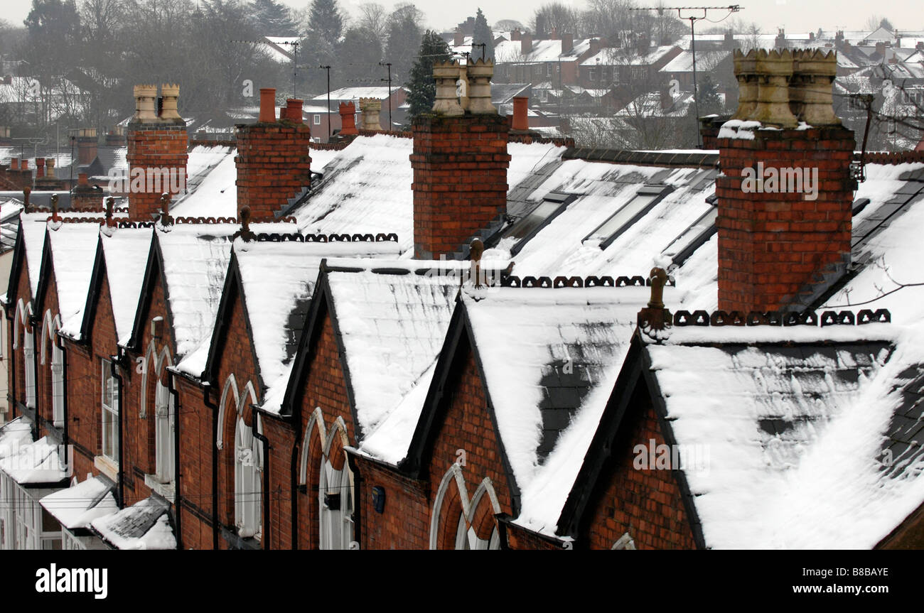 Los techos cubiertos de nieve con chimeneas de casas adosadas en un suburbio de Birmingham, demostrando un buen aislamiento del techo. Foto de stock