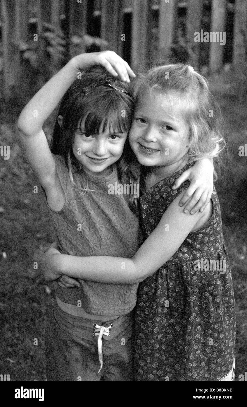 Dos niñas abrazando sonriente, B/W Foto de stock