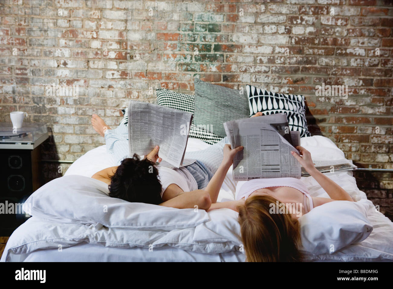 Pareja leyendo los periódicos en la cama Foto de stock