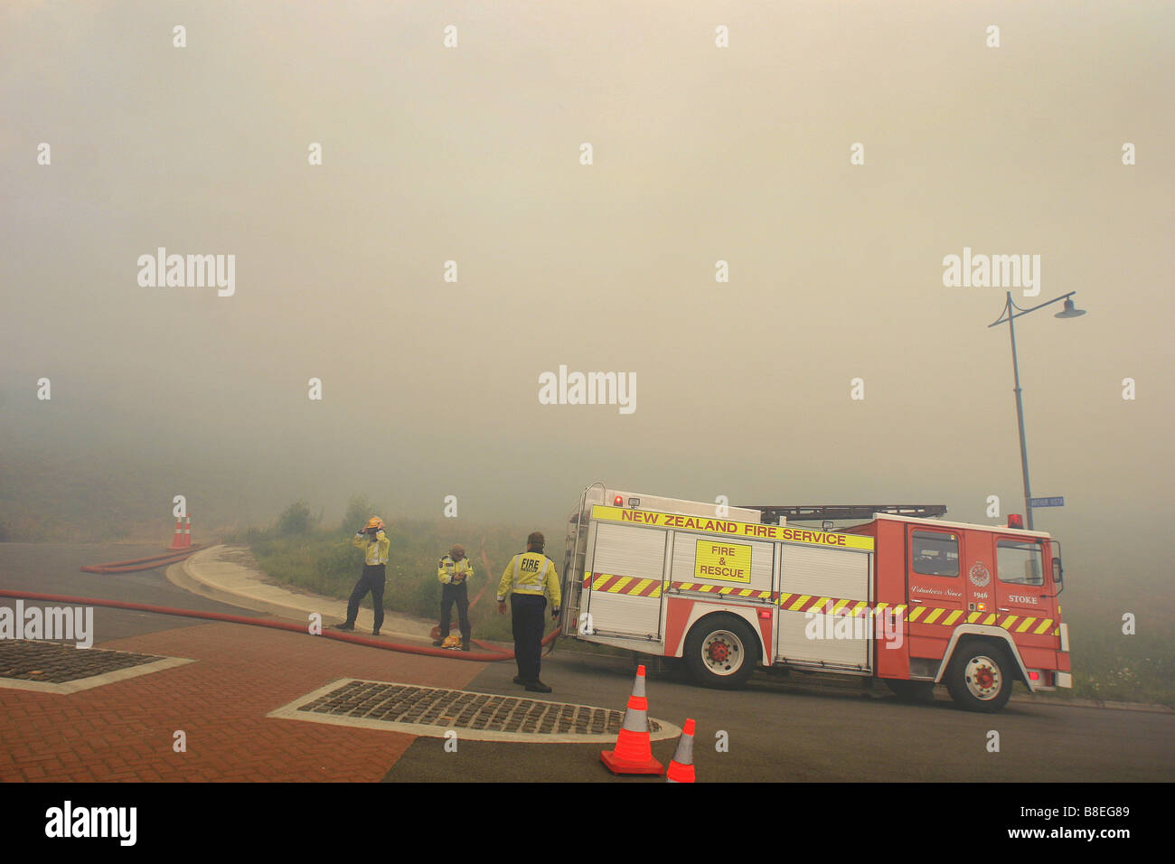 Los bomberos se preparan para librar una dichas quemas raging cerca de propiedades en Nueva Zelanda Foto de stock