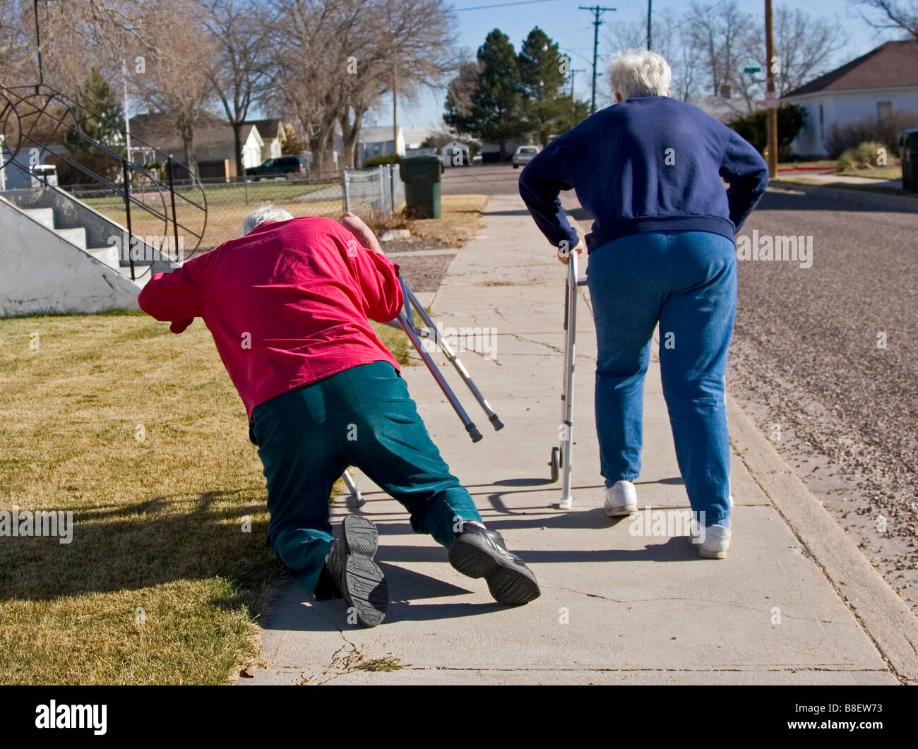 Dos ancianos jubilados andando el uso de andadores, la mujer ha disparado el hombre que está cayendo, gracioso, 1 de 4 en serie Foto de stock