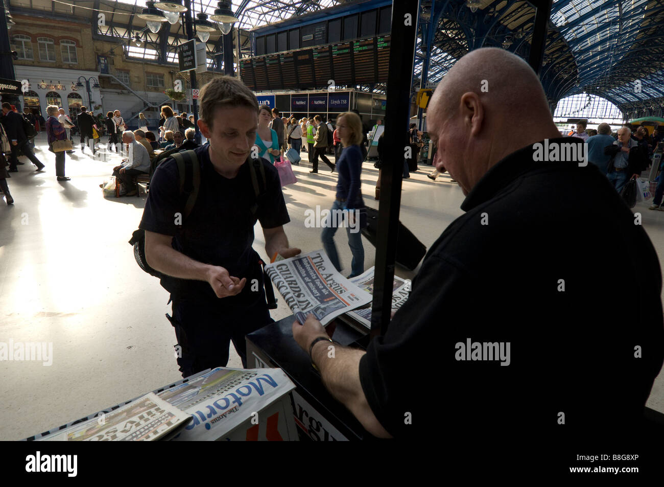 Un proveedor de noticias en una estación ferroviaria vender un papel masculino a un viajero. Foto de stock