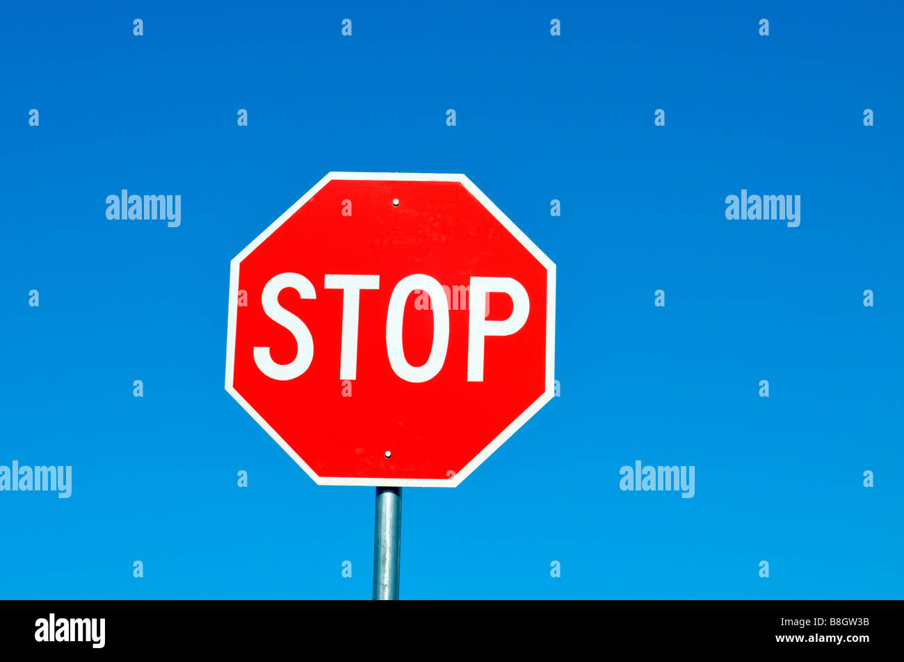 Señal de stop rojo y blanco sólido contra el cielo azul claro Foto de stock