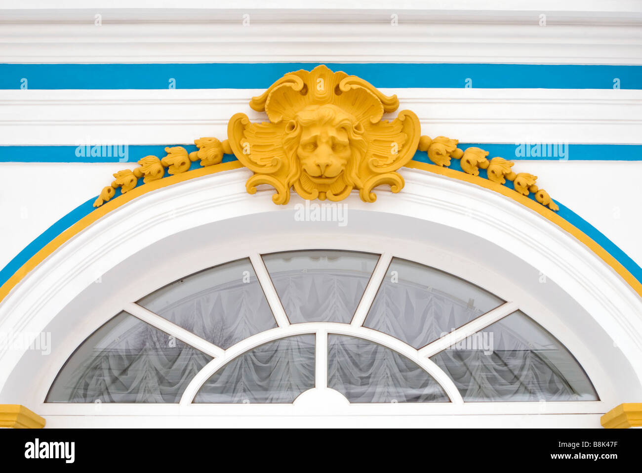 Palacio ruso decoración de paredes amarillo bajorrelieve de cabeza de león en la ventana arqueada. Foto de stock