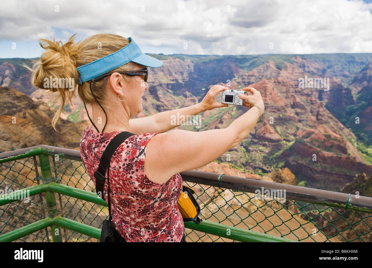 Mujer de mediana edad de tomar una imagen digital de un mirador con vistas a Waimea Canyon Waimea Canyon State Park en Kauai Hawaii EE.UU. Foto de stock