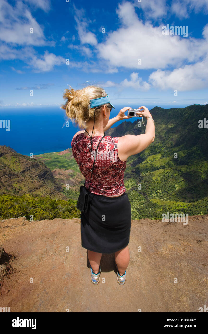 Mujer de mediana edad de tomar una imagen digital de un mirador con vistas sobre el Valle Kalalau Costa Na Pali Kauai Hawaii EE.UU. Foto de stock