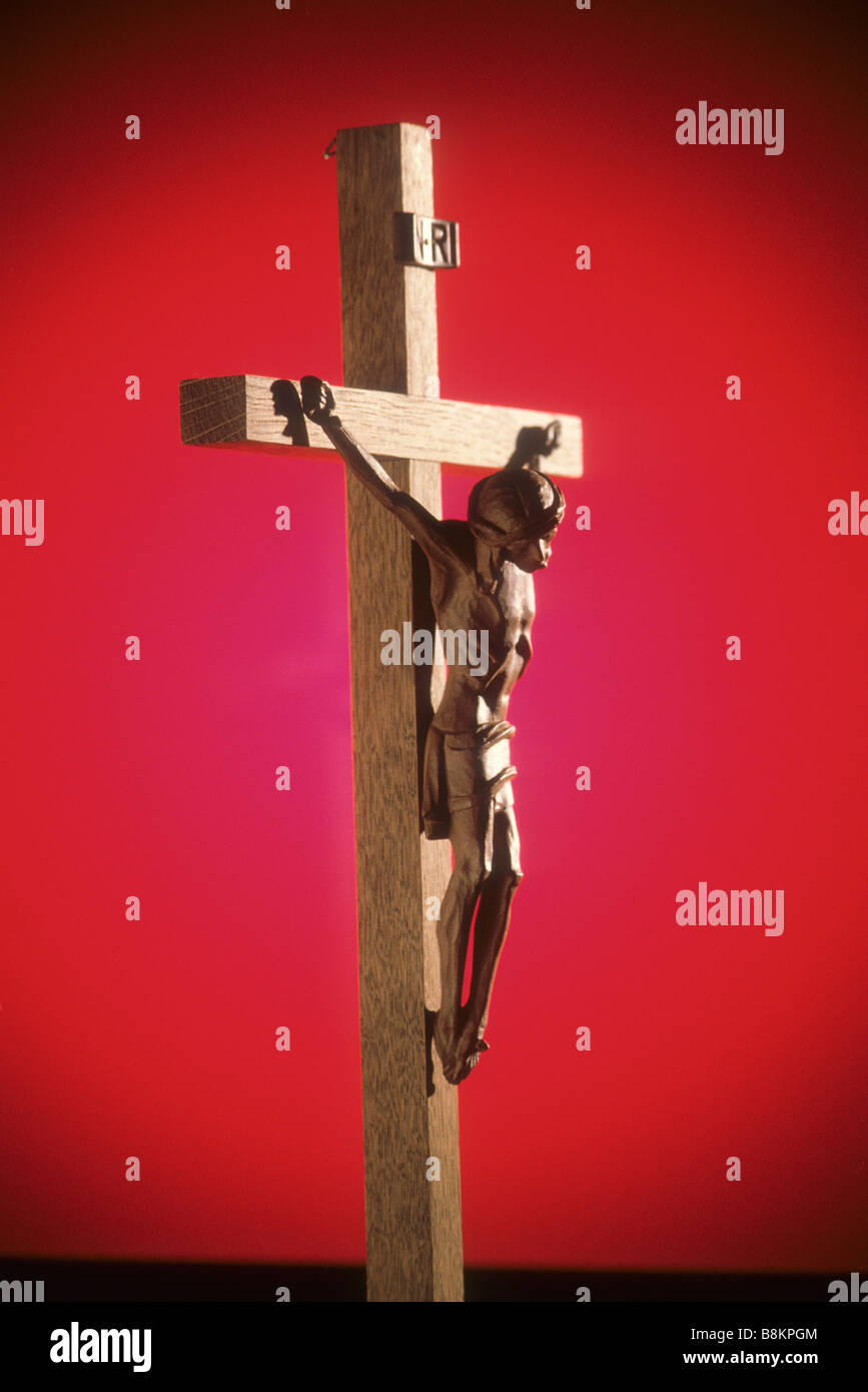 Crucifijo de madera tallada contra deep crimson antecedentes Foto de stock