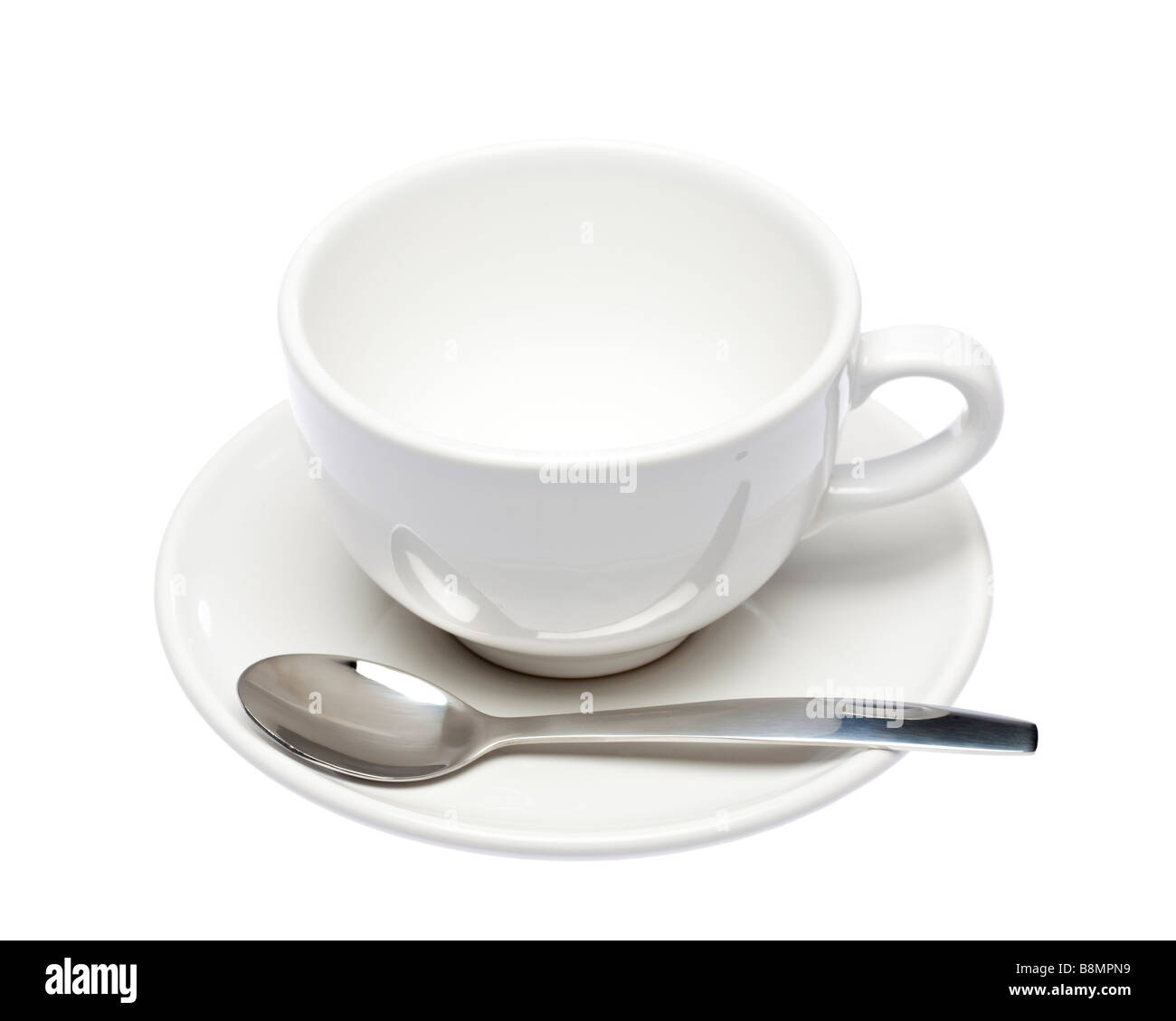 Taza y plato blanco vacío con una cuchara en el recorte de blanco Foto de stock