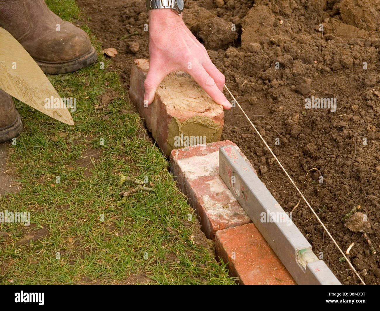 Poniendo un ladrillo de borde a jardín de césped Fotografía de stock - Alamy