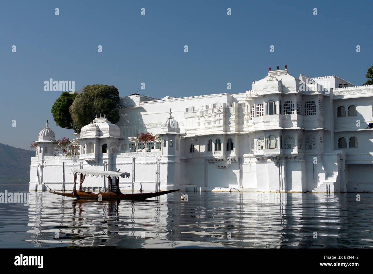 Vista del lago palace hotel en el lago pichola con reflejos de sol y cielo azul Foto de stock