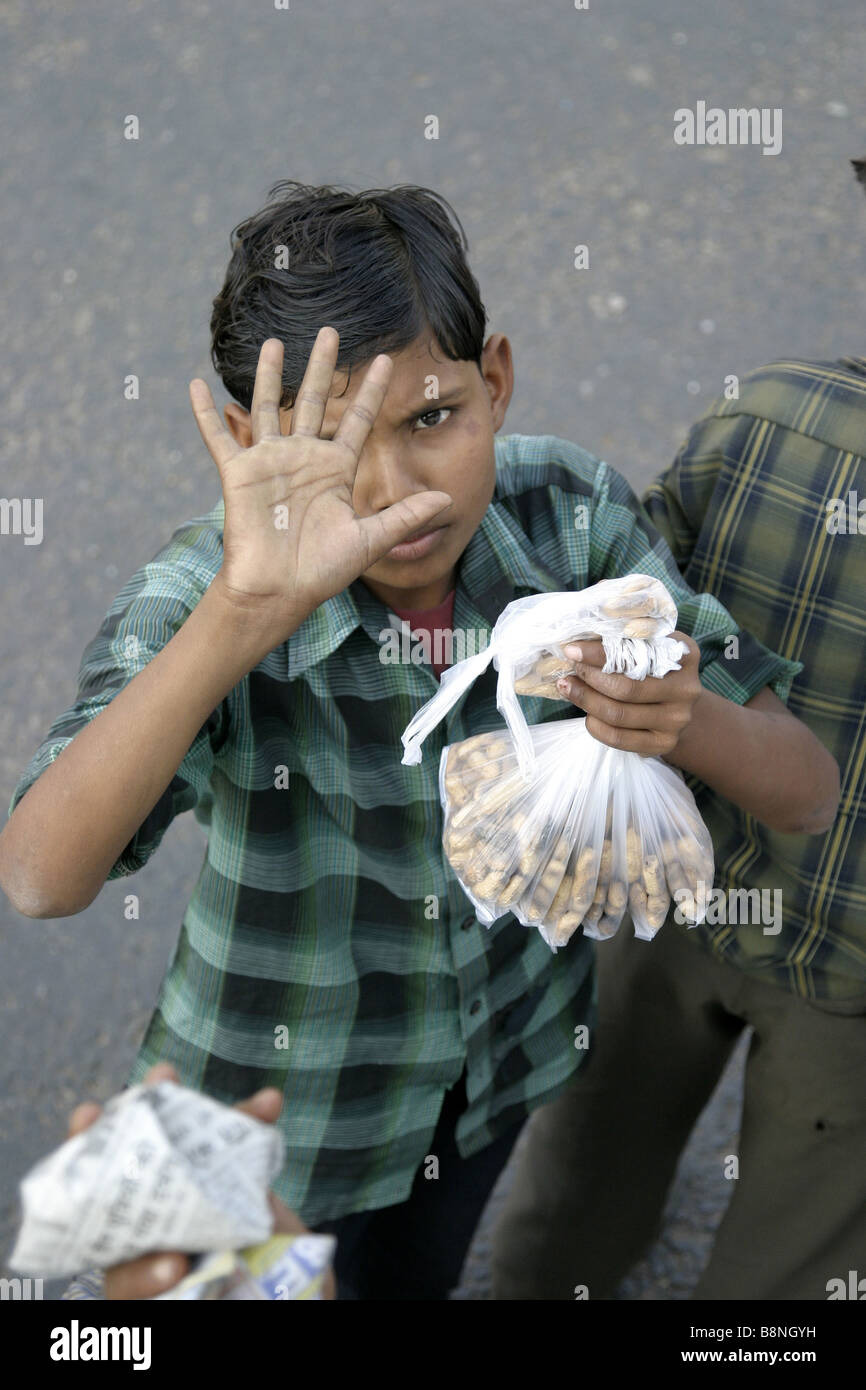 Joven vende maní de cinco rupias para viajeros de autobús en India Foto de stock