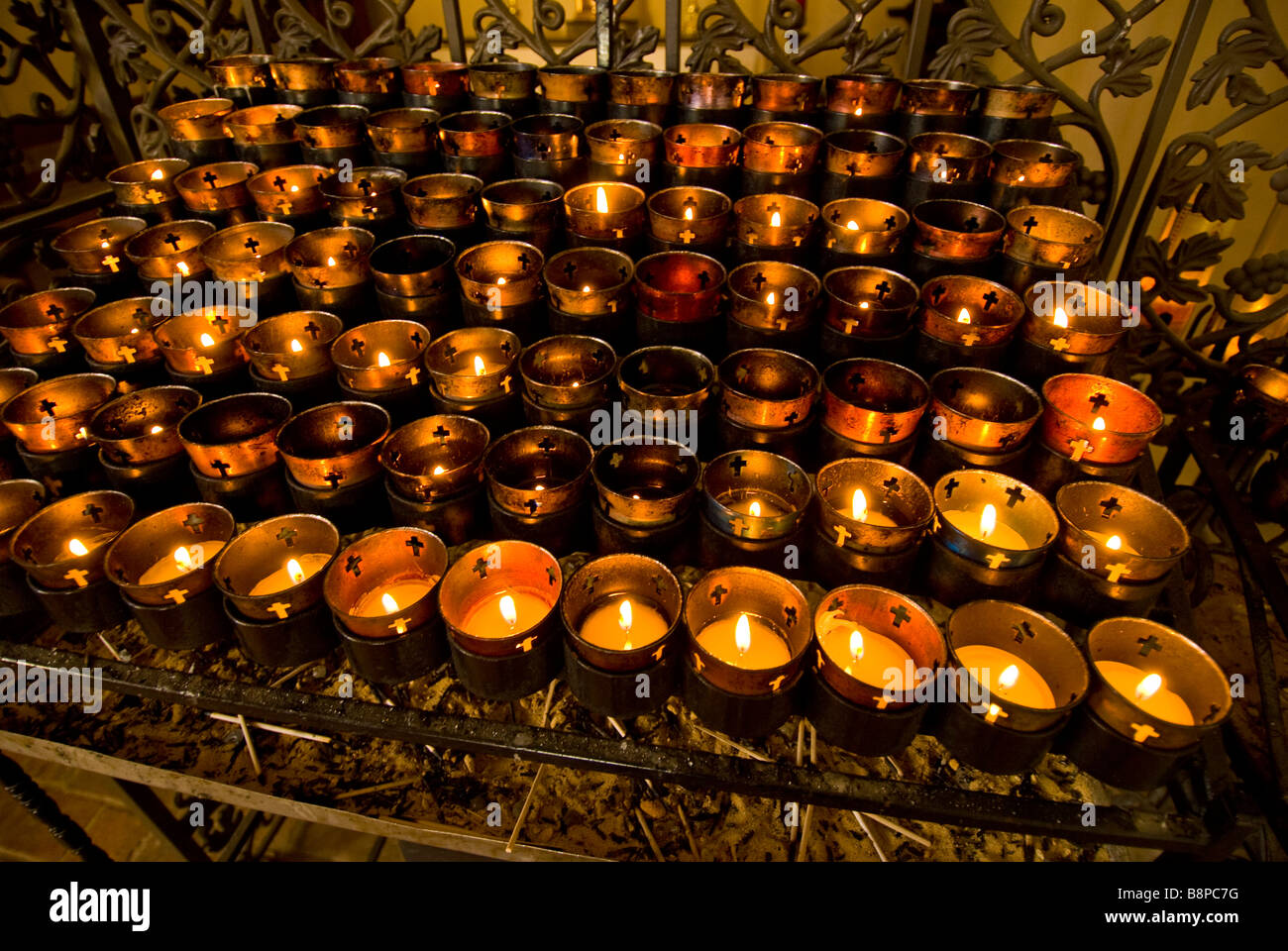 Velas votivas en el interior del templo de rack docenas de velas ceremonia religiosa práctica personalizada Foto de stock