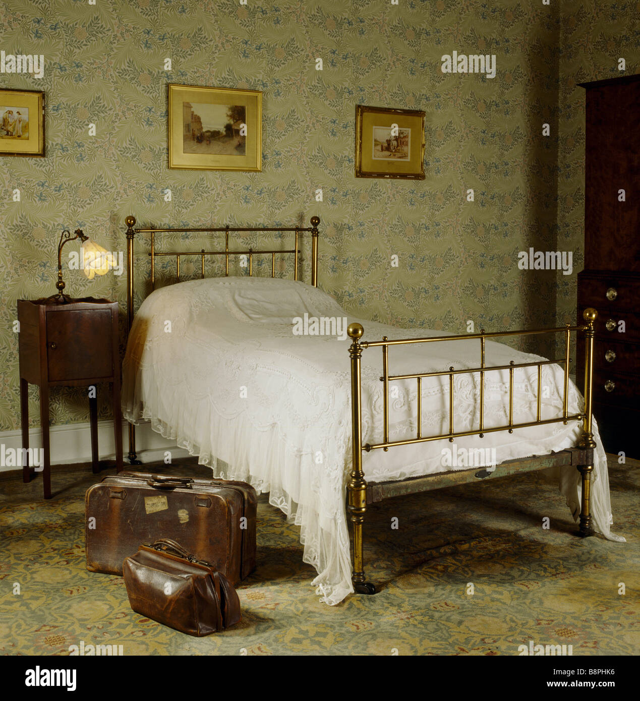 El Larkspur en Standen dormitorio con una cama del cura una vieja maleta de  cuero y bolsas y papel tapiz de William Morris Fotografía de stock - Alamy