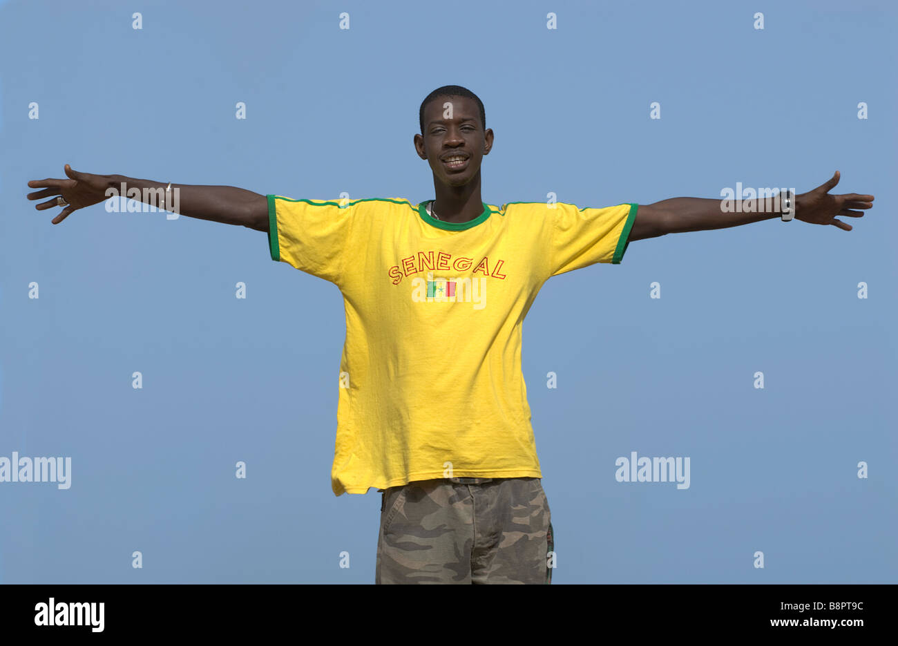 Hombre africano de pie brazos abiertos usando el equipo de fútbol de Senegal colores amarillo y verde camiseta Foto de stock