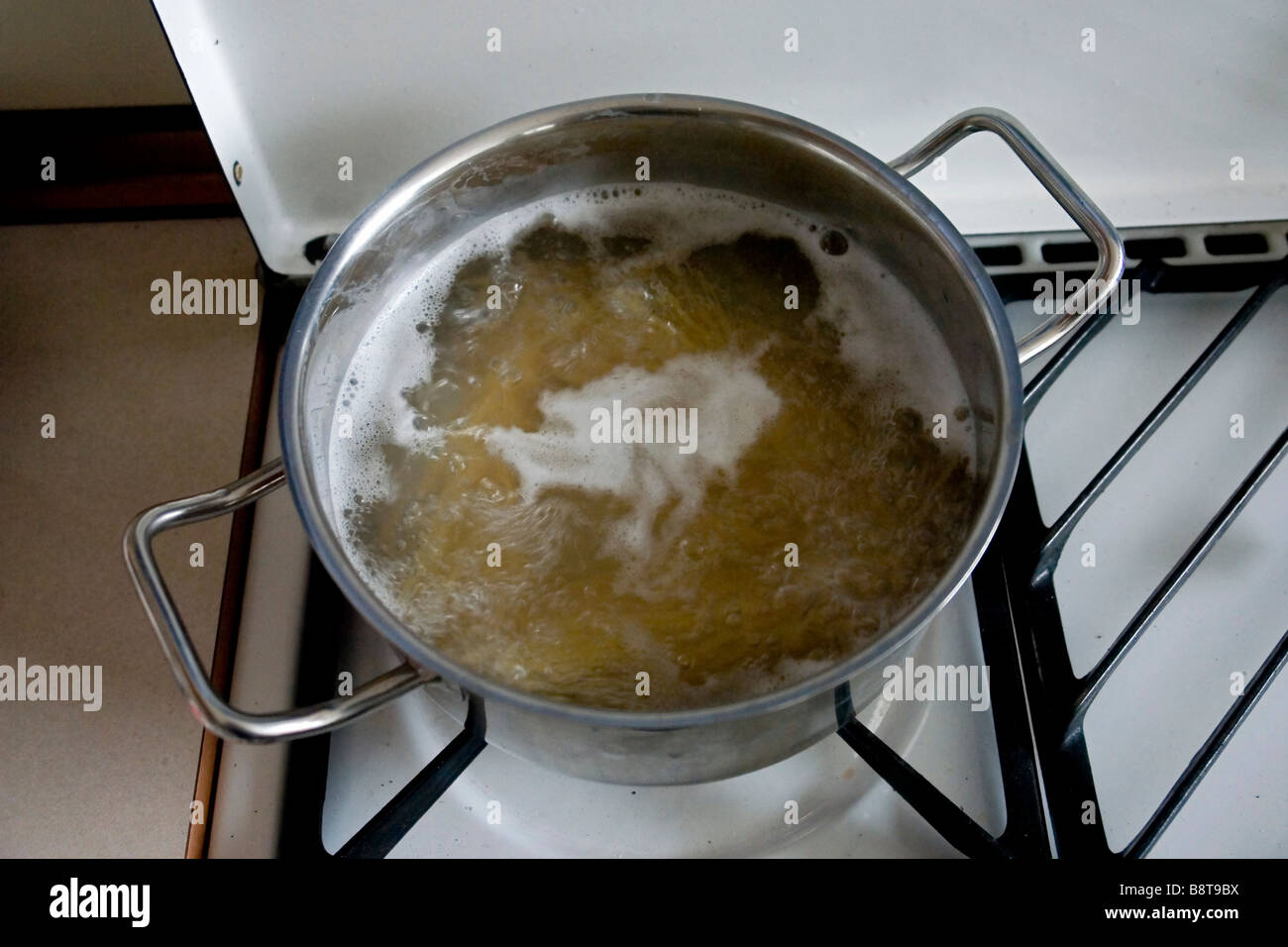 Cocinar los espaguetis en agua hirviendo en una cazuela de metal Foto de stock