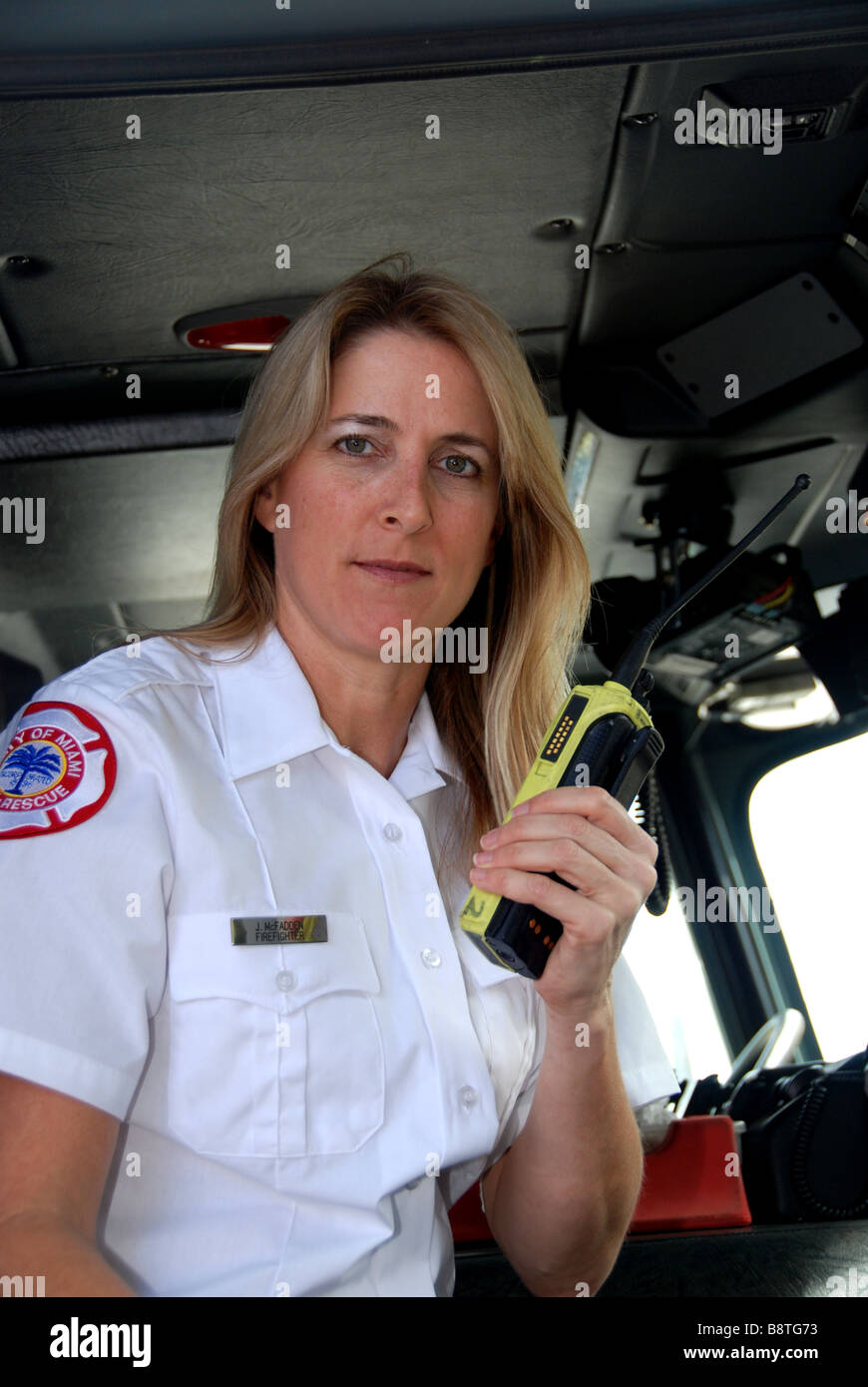 Mujeres bombero paramédico EMT en uniforme de vestir hablando por radio de  dos vías en el interior de la cabina del motor de fuego Fotografía de stock  - Alamy