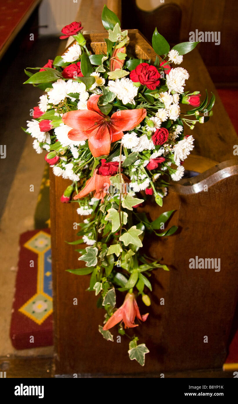 Un ramo de flores conectado al lado de una iglesia pew en celebración de una boda. Foto de stock