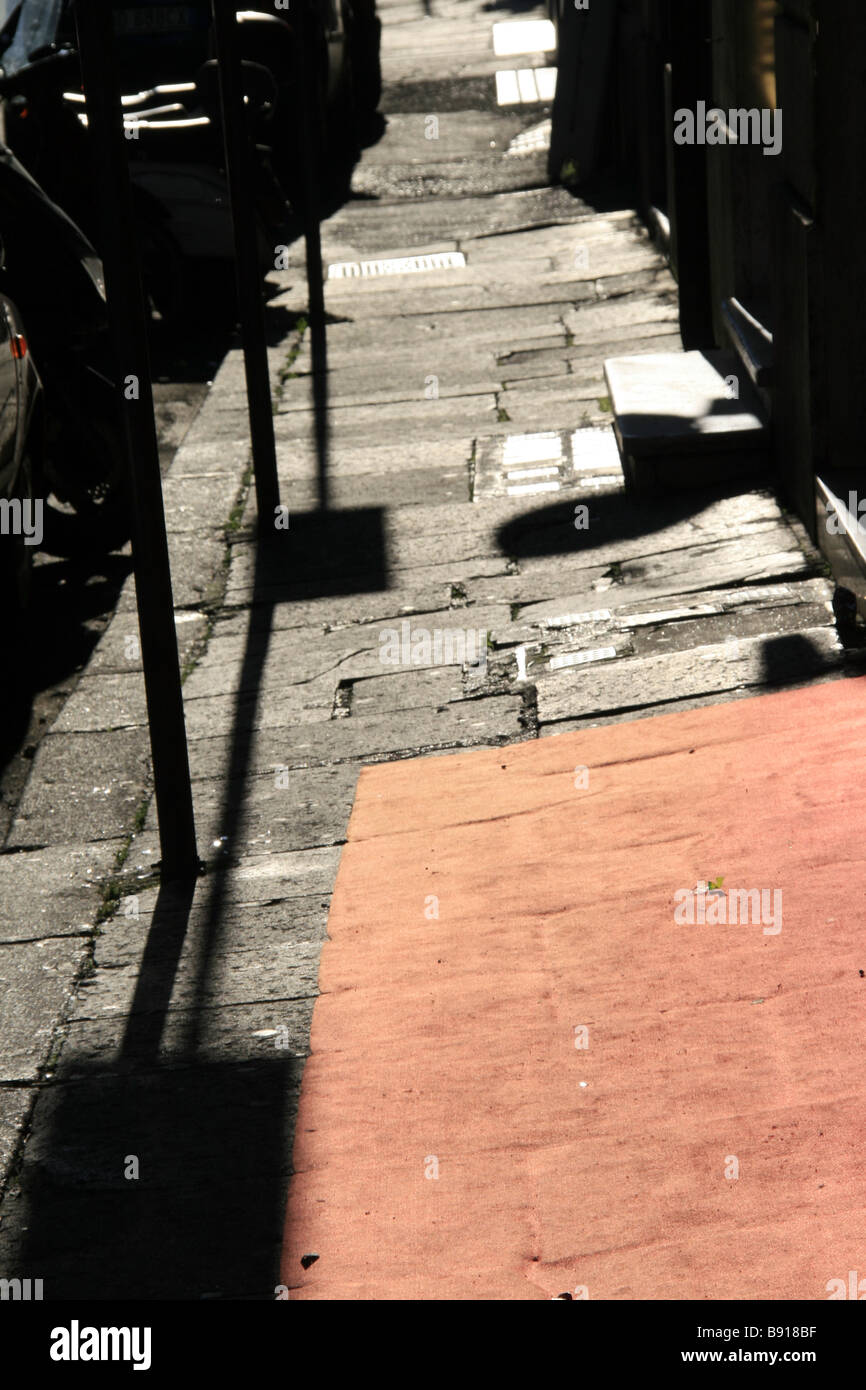 Una vieja y sucia alfombra roja fuera de tienda en vacante vacía acera en la ciudad de sun Foto de stock