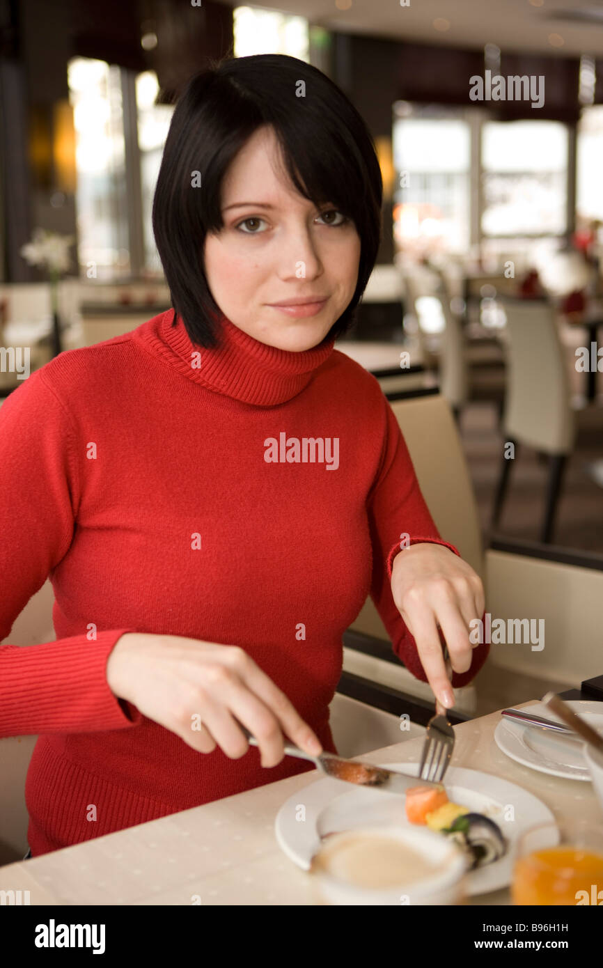 Frau schneidet essen im Restaurante (Fruehstueck) Foto de stock
