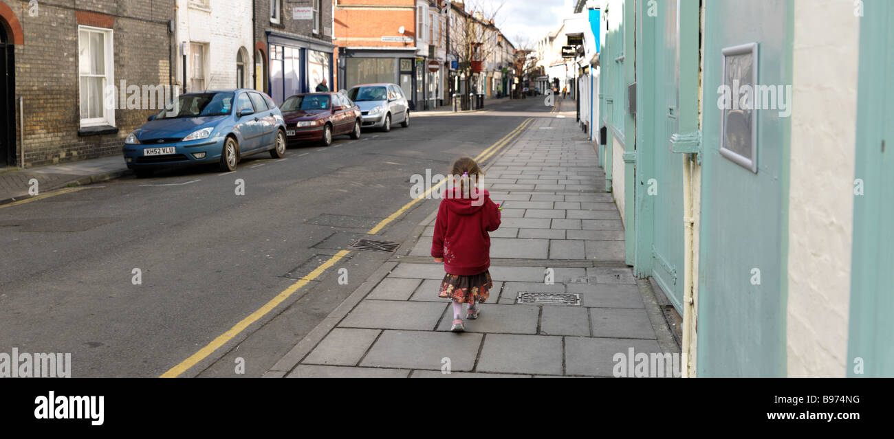 Cinco años de edad, niña caminando en una calle de Salisbury, Wiltshire Foto de stock