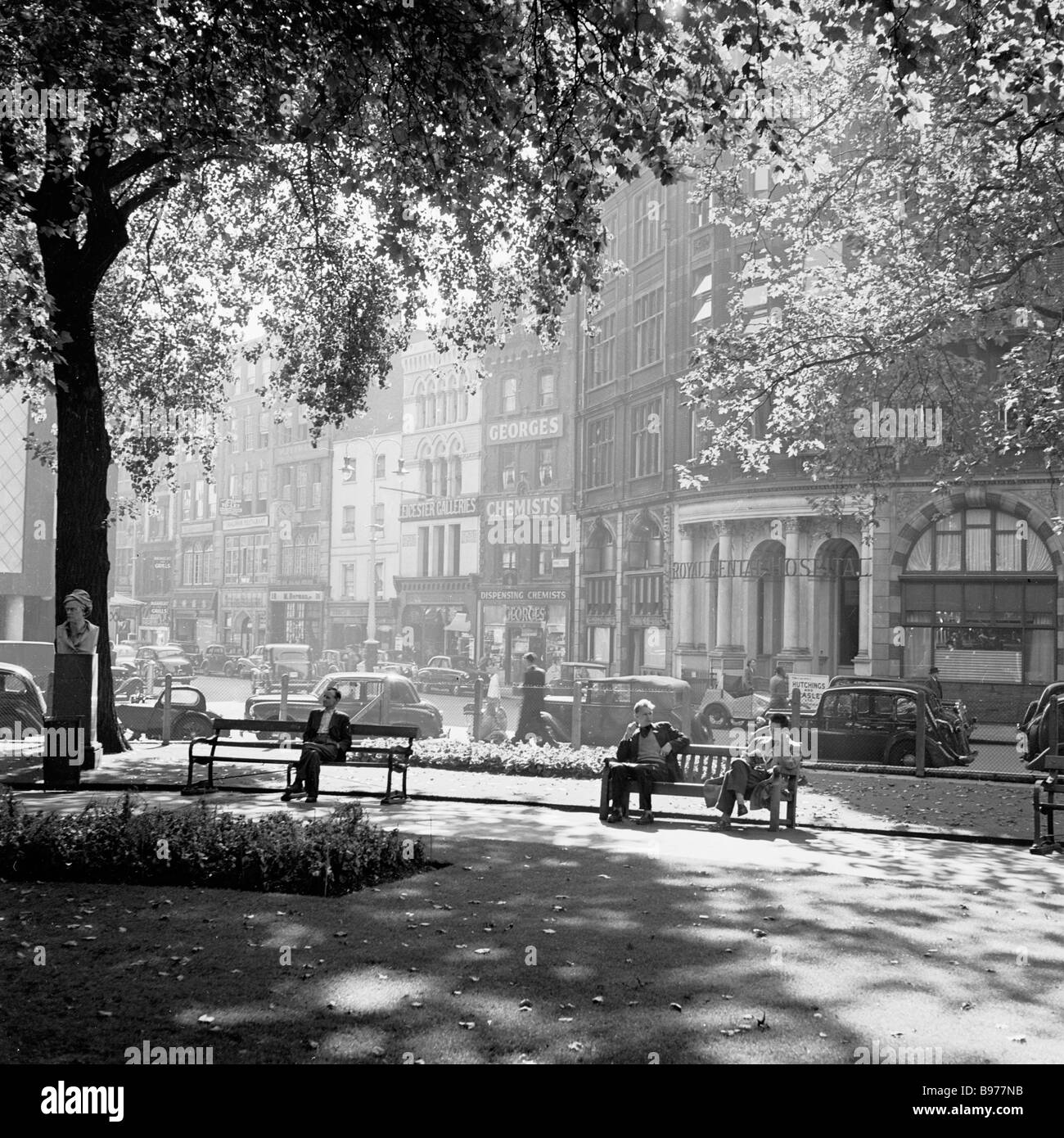 Personas sentadas en los banquillos disfrutando de un lugar tranquilo en el sol en Leicester Square, London's West End en esta imagen por J Allan efectivo desde la década de 1950. Foto de stock