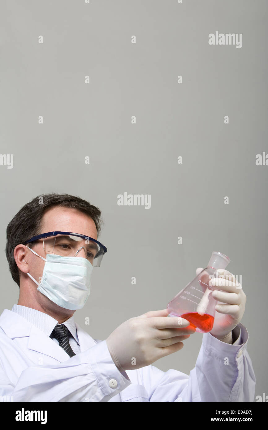 Scientist examina el líquido en el vaso Foto de stock