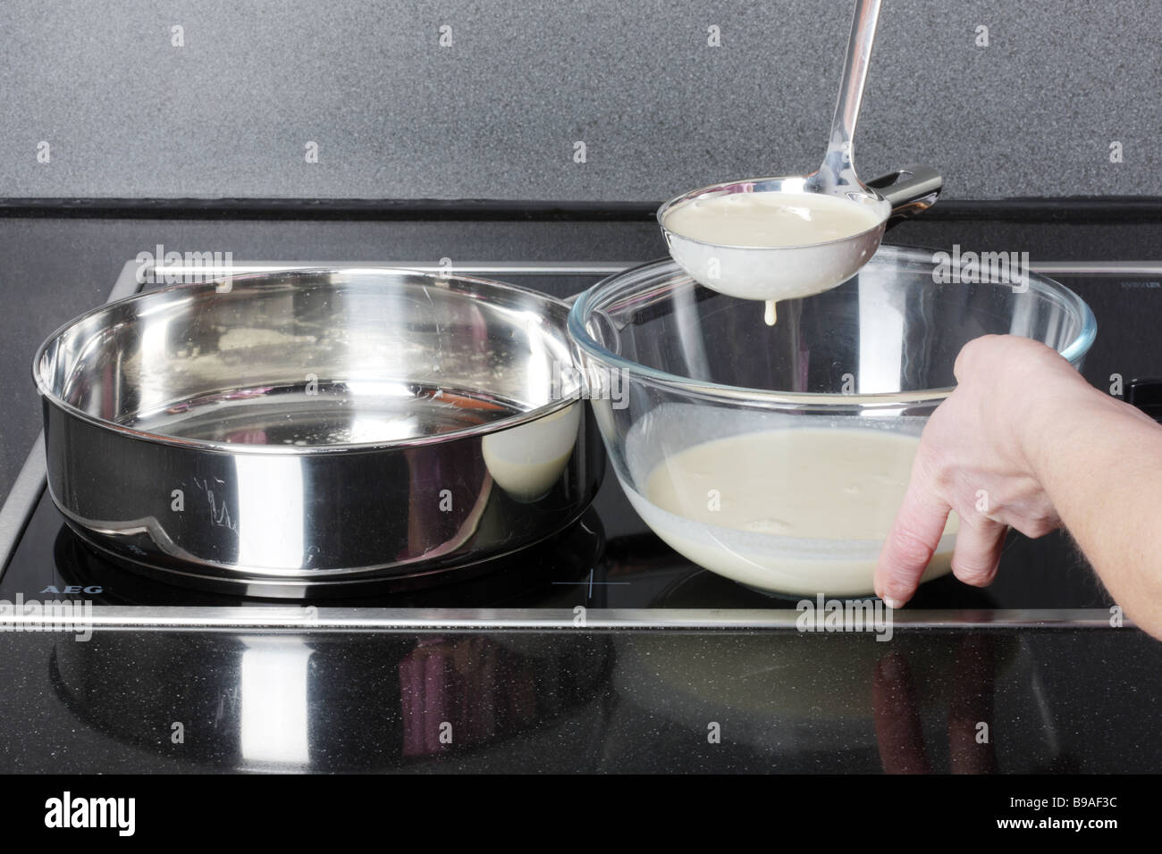 Mujer Añadir Pancake mezcla a la sartén Foto de stock