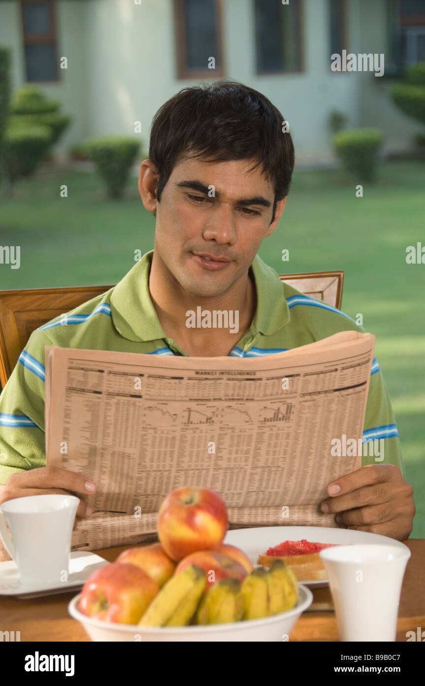 Hombre Leyendo Un Periódico En Una Mesa De Desayuno Fotografía De Stock Alamy