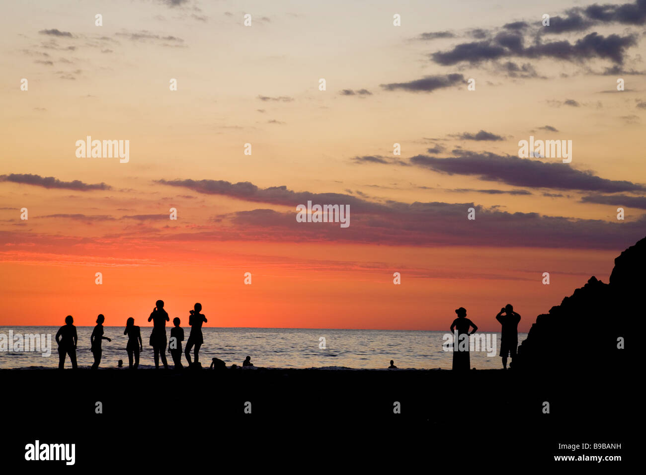 Silueta de personas reunidas en la playa para ver la puesta del sol en Manuel Antonio, Costa Rica. Foto de stock