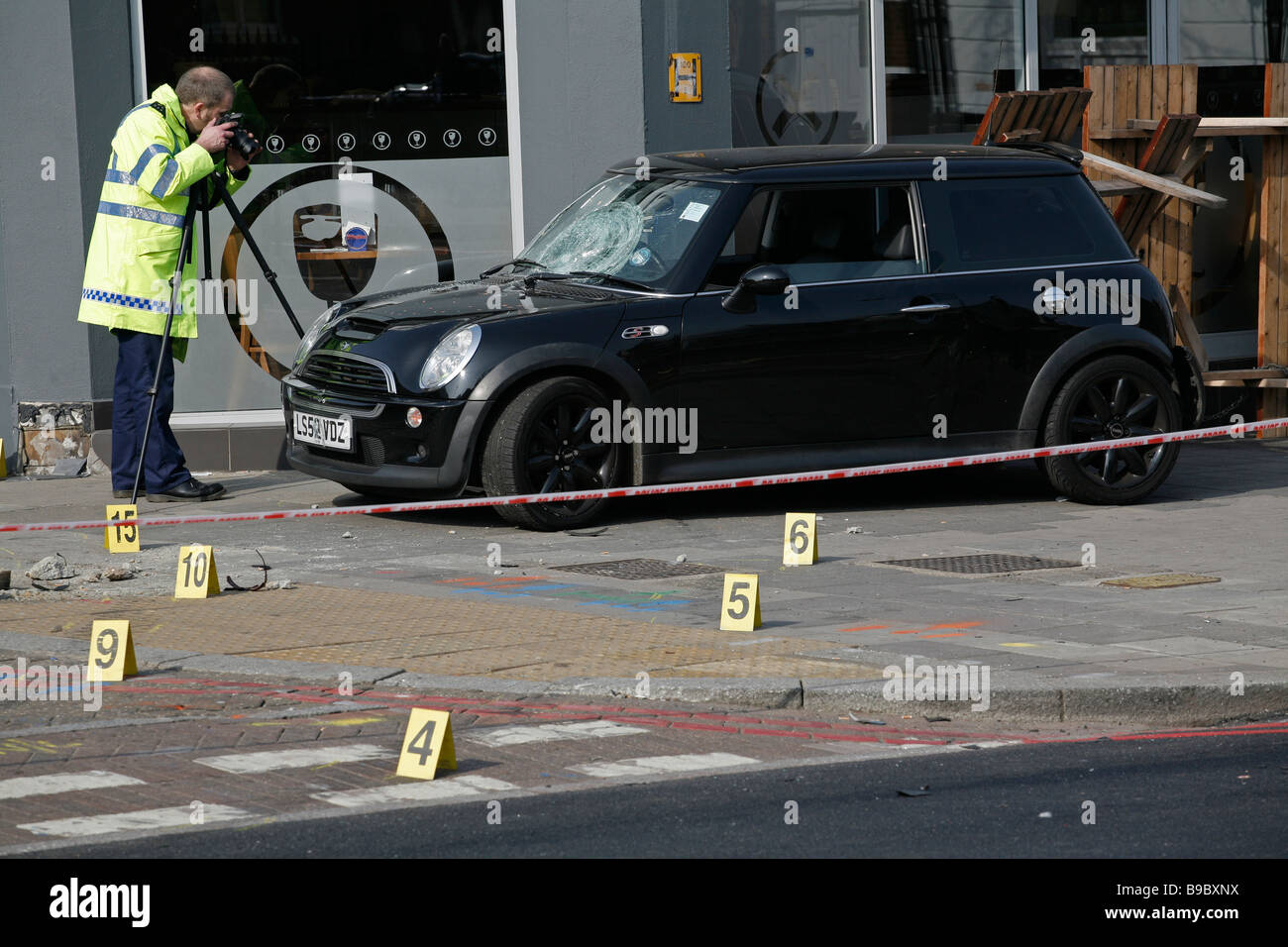 La policía forense tomar pruebas después de un accidente de tráfico deja el coche en la acera, en Clapham High Street, al sur de Londres. Foto de stock