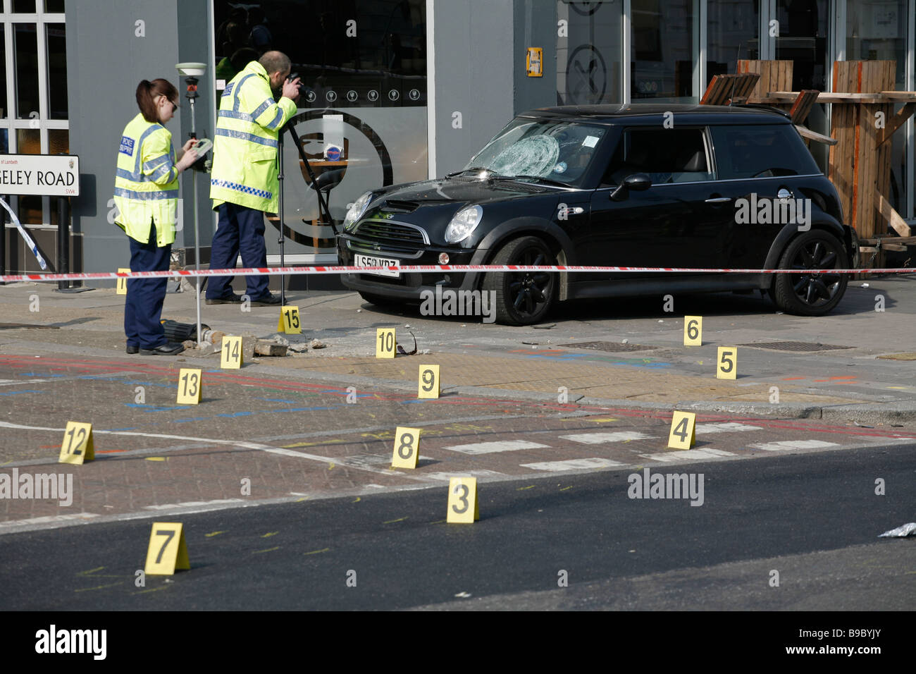 La policía forense tomar pruebas después de un accidente de tráfico deja el coche en la acera, en Clapham High Street, al sur de Londres. Foto de stock