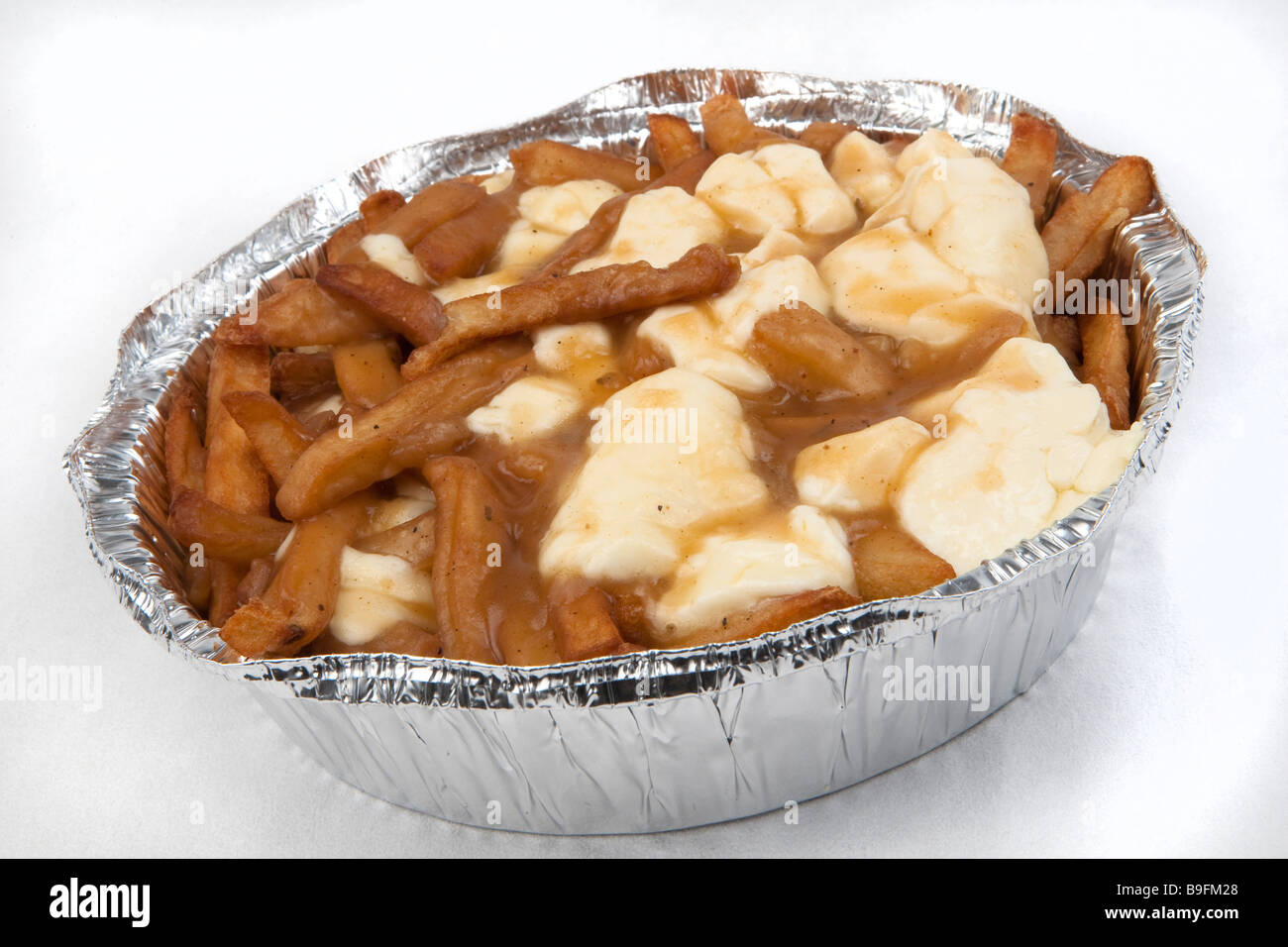 Una poutine sobre un fondo blanco poutine es un plato francés canadiense compuesto de papas fritas, coronado con queso fresco cuajada Foto de stock
