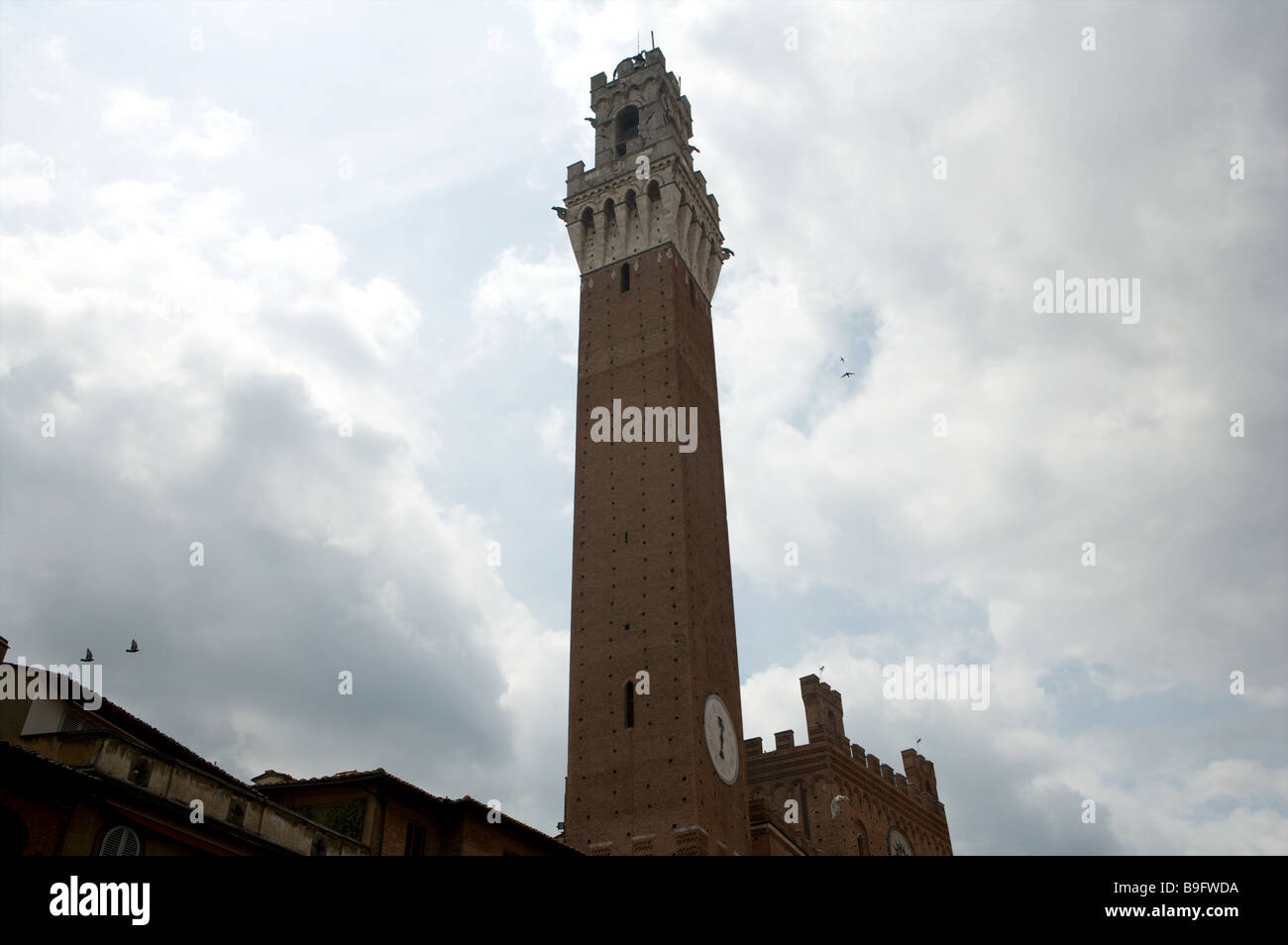 La torre principal de la Torres de Mangia en la plaza llamada Piazza Il Campo bajo un cielo gris en Siena Italia Foto de stock