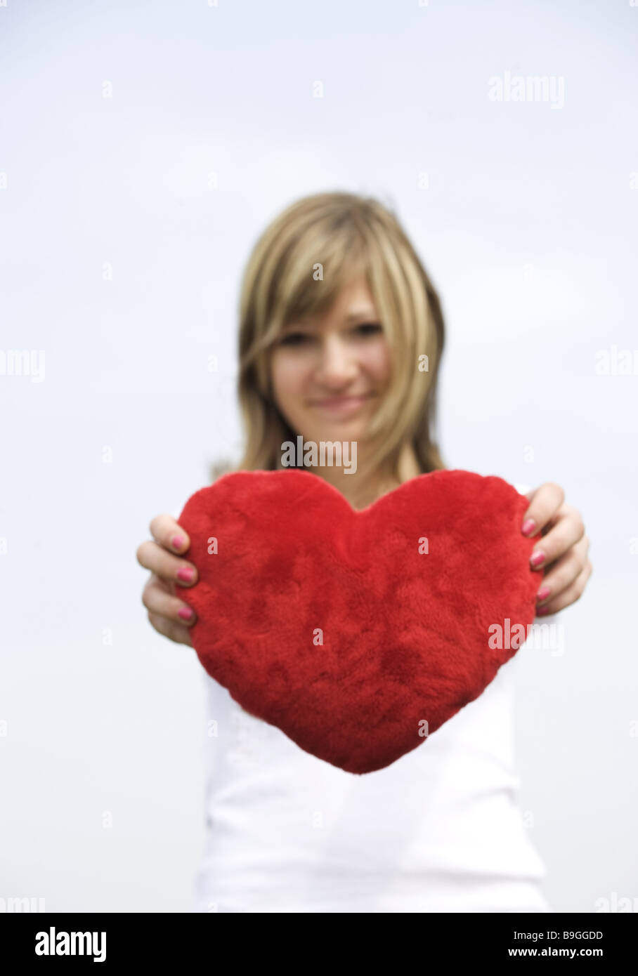 Mujer joven feliz celebración del corazón de felpa retrato borrosidad jóvenes chica joven de 14 años de corazón amor-símbolo símbolo de amor Foto de stock
