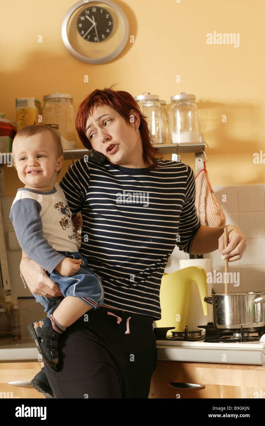 Cocina madre niño lleva la estufa cocineros teléfonos simultáneamente detalle series personas niño varón mujer Foto de stock