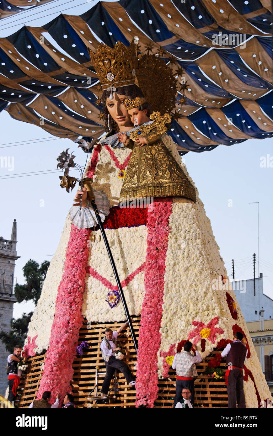 Los hombres colocando ofrendas florales en la réplica de madera grande estatua de la Virgen de los Desamparados. Festival de Las Fallas Valencia España Foto de stock